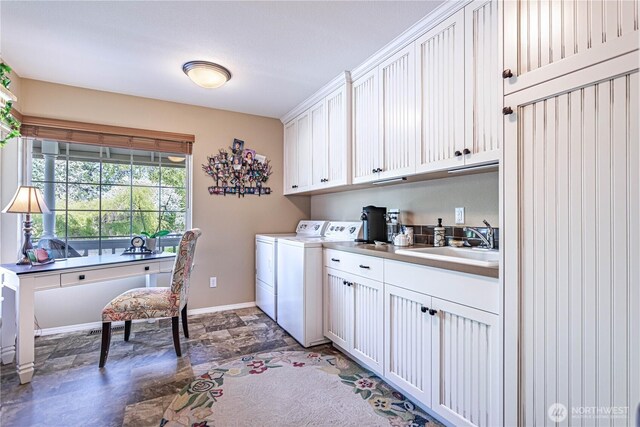 clothes washing area with a sink, cabinet space, washing machine and dryer, stone finish flooring, and baseboards