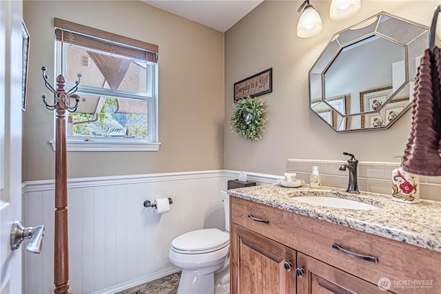 bathroom featuring toilet, wainscoting, and vanity
