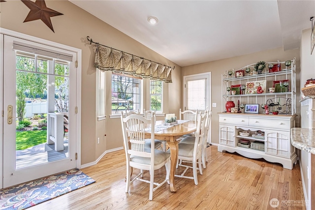dining area featuring a wealth of natural light, light wood finished floors, vaulted ceiling, and baseboards