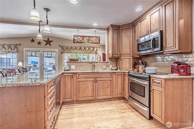 kitchen with a sink, appliances with stainless steel finishes, light wood finished floors, a peninsula, and vaulted ceiling with beams