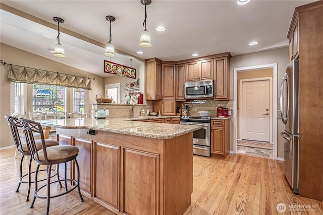 kitchen featuring a kitchen bar, tasteful backsplash, a peninsula, appliances with stainless steel finishes, and lofted ceiling