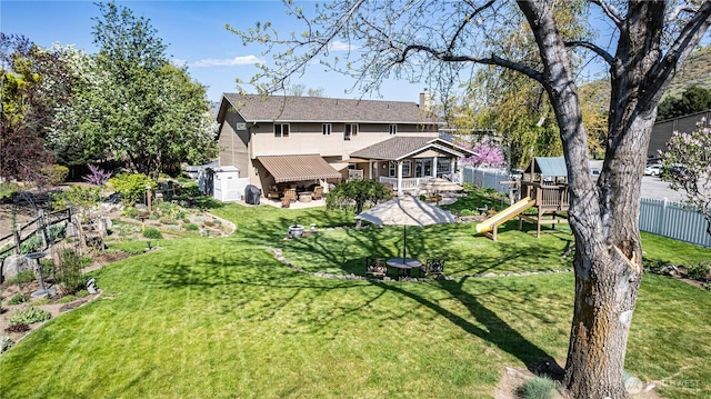exterior space featuring a lawn, a chimney, a playground, and fence