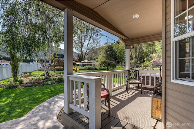 deck with covered porch, fence, and a lawn