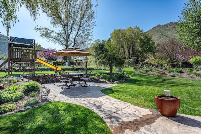 view of community featuring a lawn, playground community, and a mountain view