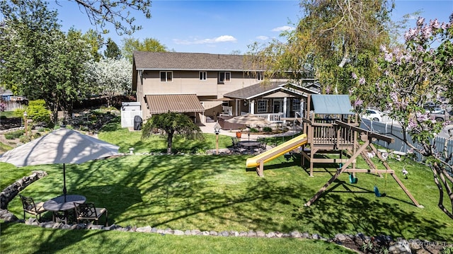 rear view of house with a playground and a lawn