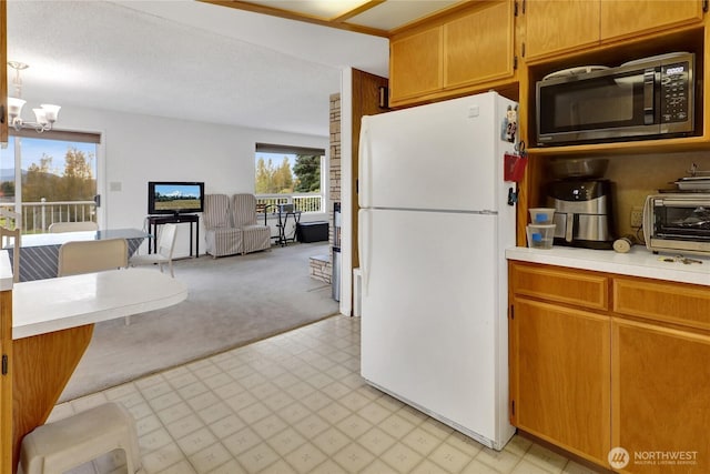 kitchen featuring light floors, light colored carpet, freestanding refrigerator, light countertops, and a notable chandelier