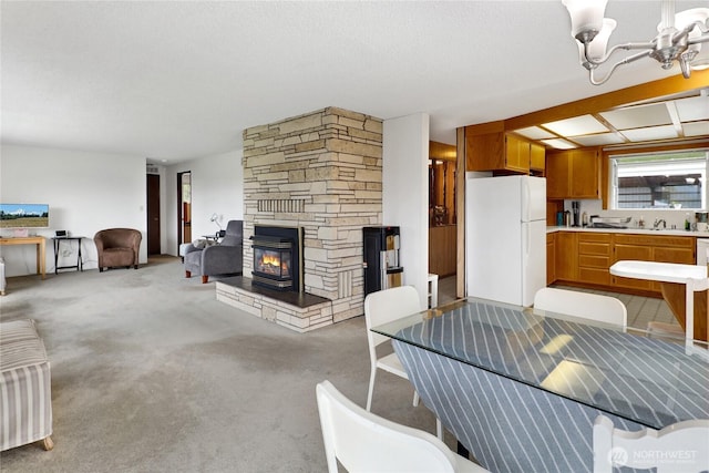 living room with a stone fireplace, light carpet, and a chandelier