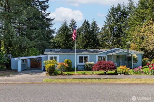 ranch-style house featuring aphalt driveway, covered porch, and an attached carport