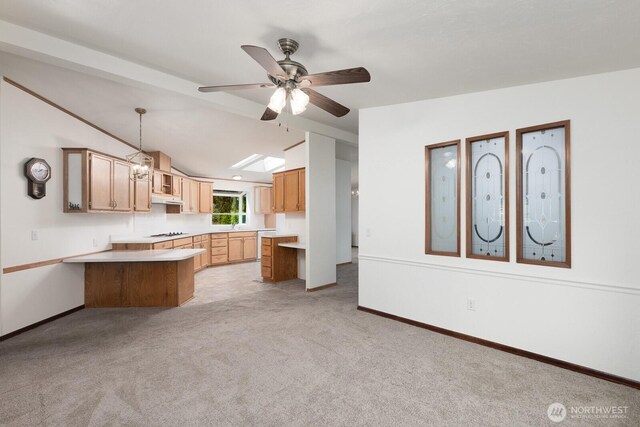 kitchen with a peninsula, ceiling fan, light colored carpet, light countertops, and vaulted ceiling