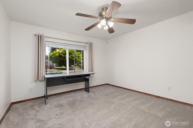 carpeted spare room featuring baseboards and ceiling fan