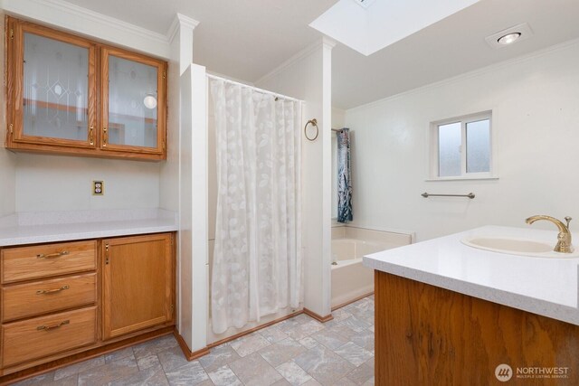 bathroom featuring crown molding, vanity, a bath, stone finish flooring, and a skylight