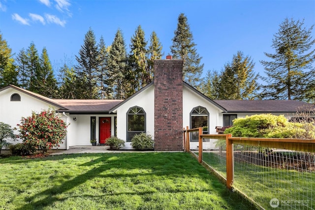 ranch-style home featuring a chimney, fence, stucco siding, and a front yard