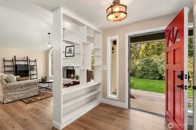 interior space with a lit fireplace, wood finished floors, and baseboards