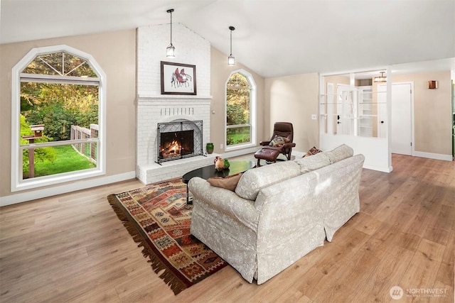 living area with vaulted ceiling, wood finished floors, and plenty of natural light