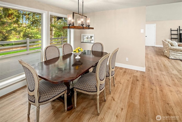 dining space featuring an inviting chandelier, baseboards, and light wood-style floors