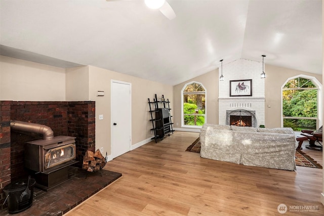 living area with a wealth of natural light, a ceiling fan, light wood-style floors, and lofted ceiling