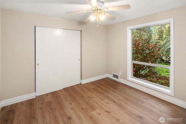 unfurnished bedroom with light wood-style floors, a closet, ceiling fan, visible vents, and baseboards