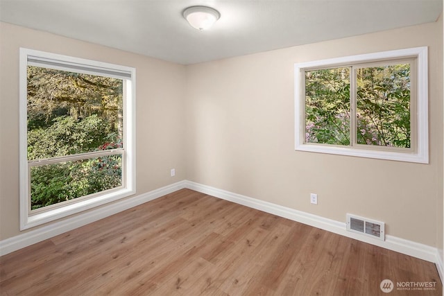 unfurnished room with wood finished floors, visible vents, and baseboards