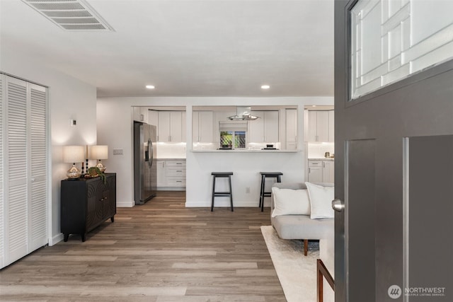 interior space featuring visible vents, light wood-type flooring, recessed lighting, and baseboards