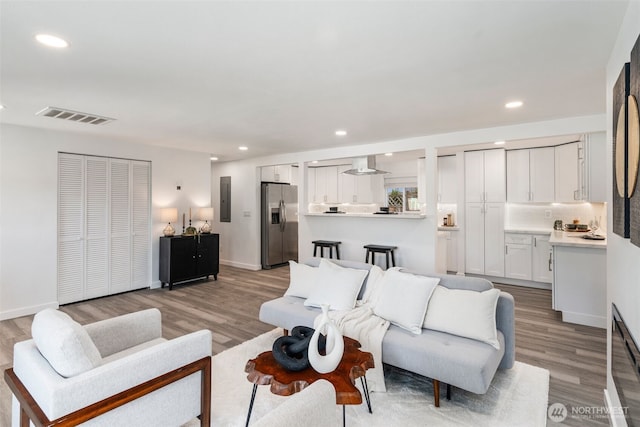 living room with recessed lighting, visible vents, light wood-style flooring, and baseboards