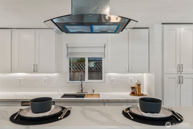 kitchen featuring range hood, a sink, white cabinetry, and decorative backsplash
