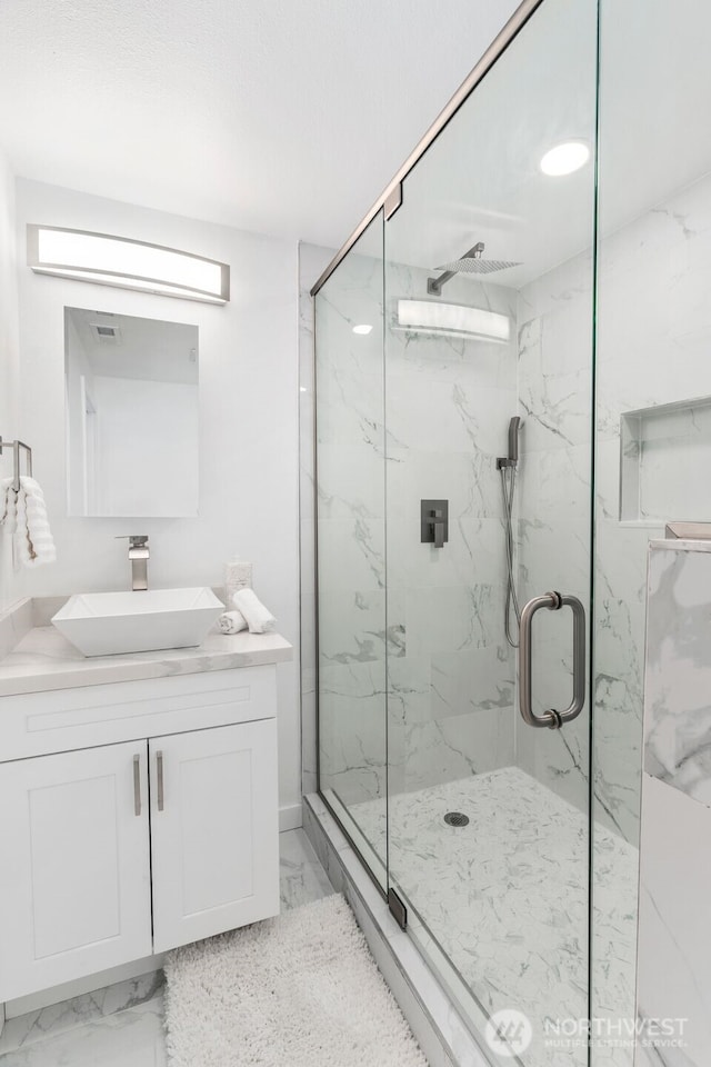 bathroom featuring visible vents, a marble finish shower, vanity, and marble finish floor