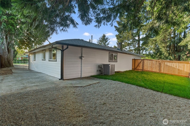 back of property featuring fence, central AC unit, and a yard