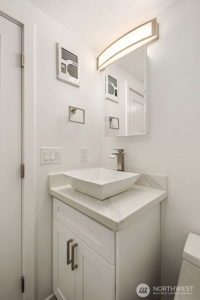 bathroom with toilet, visible vents, and vanity