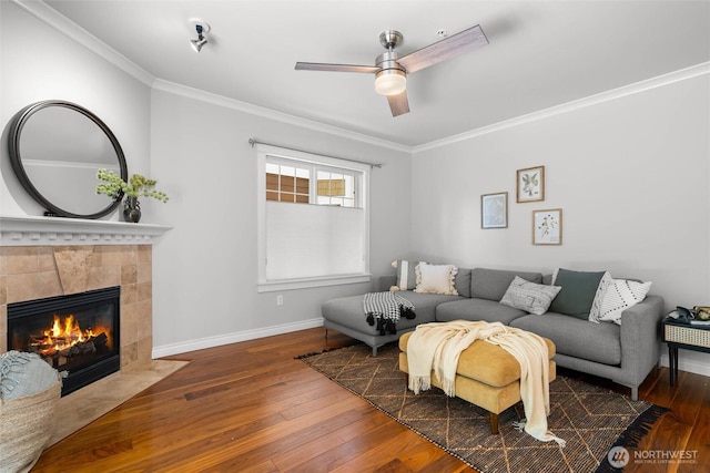 living area featuring baseboards, ornamental molding, a fireplace, and hardwood / wood-style floors