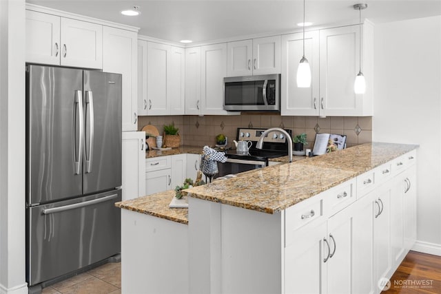 kitchen with recessed lighting, a peninsula, appliances with stainless steel finishes, and light stone countertops
