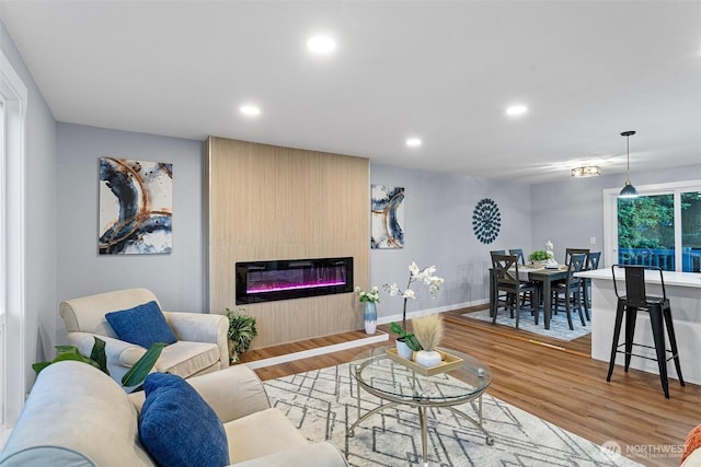 living area with recessed lighting, baseboards, wood finished floors, and a glass covered fireplace