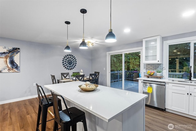 kitchen with white cabinetry, light countertops, a center island, dishwasher, and dark wood-type flooring