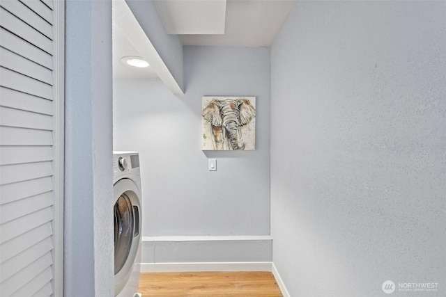 laundry room featuring laundry area, wood finished floors, washer / dryer, and baseboards