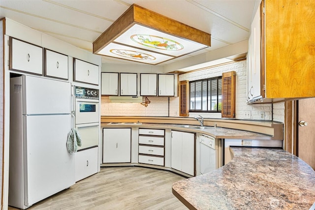 kitchen with white appliances, light wood finished floors, white cabinetry, and a sink