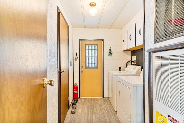 laundry room with cabinet space, washing machine and dryer, light wood-style flooring, and a heating unit