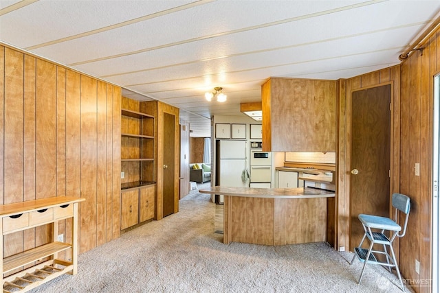 kitchen featuring wood walls, light carpet, brown cabinets, built in shelves, and a peninsula