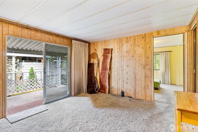 spare room with carpet and wooden walls
