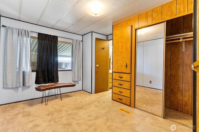 bedroom featuring carpet flooring, a textured ceiling, and wooden walls