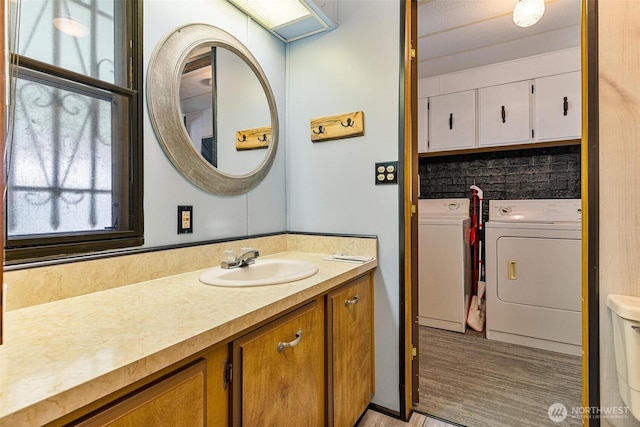 bathroom with washing machine and clothes dryer, healthy amount of natural light, vanity, and wood finished floors