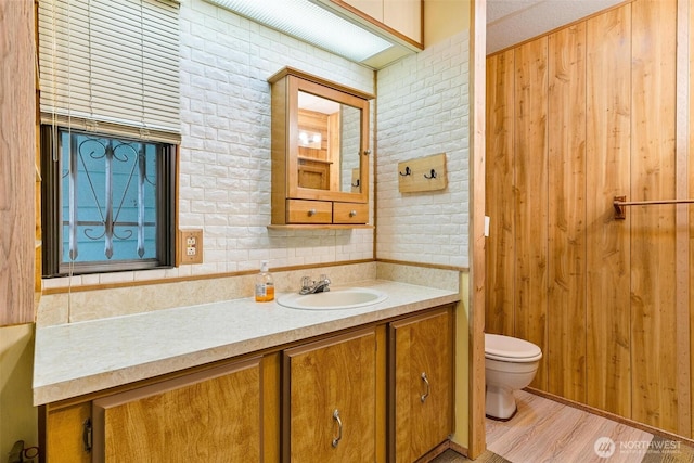 bathroom with toilet, vanity, and wood finished floors