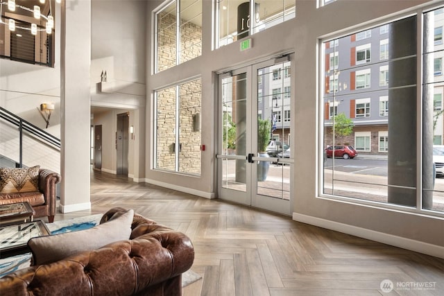 doorway to outside featuring baseboards, french doors, healthy amount of natural light, and a towering ceiling