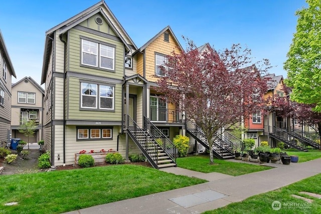multi unit property featuring stairway, board and batten siding, and a front lawn