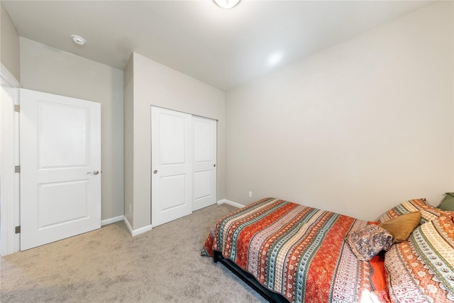 carpeted bedroom with a closet and baseboards
