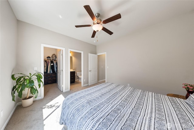 bedroom with light colored carpet, a closet, ceiling fan, a walk in closet, and baseboards