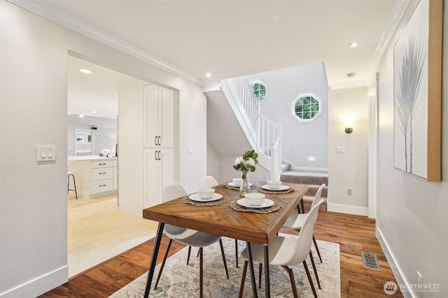 dining area featuring ornamental molding, visible vents, stairway, and light wood-style floors