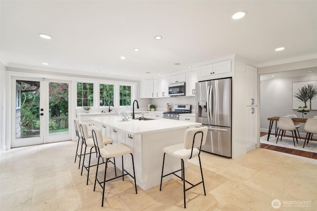 kitchen featuring white cabinetry, a sink, appliances with stainless steel finishes, a breakfast bar, and recessed lighting