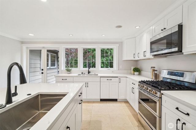 kitchen featuring appliances with stainless steel finishes, ornamental molding, white cabinets, and a sink