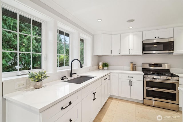 kitchen featuring a sink, light tile patterned floors, light countertops, white cabinets, and appliances with stainless steel finishes