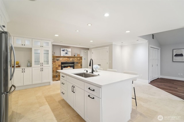 kitchen featuring stainless steel refrigerator with ice dispenser, an island with sink, white cabinets, and a sink