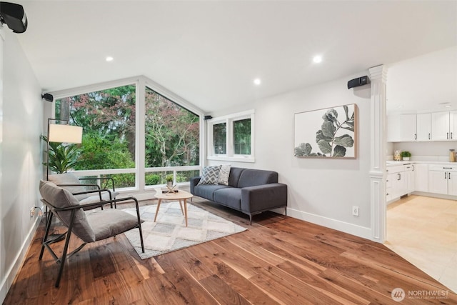 living area with recessed lighting, light wood-style floors, vaulted ceiling, baseboards, and a wall of windows